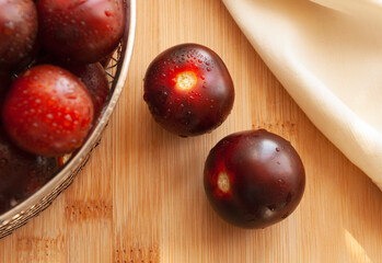Cherry tomatoes of dark red color. Small tomatoes. Berries in a box. Fabric. Cooking at home. Harvest. Food. Wooden board.
