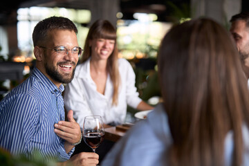 Happy entrepreneur talking to his colleagues during lunch break in restaurant.