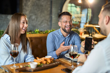 Group of happy business colleagues using cell phone during lunch in a restaurant