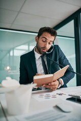 Fototapeta premium Business, man and phone call with diary in office for communication, connection and conversation. Male person, employee and telephonic meeting or multitasking for schedule, deadline and writing