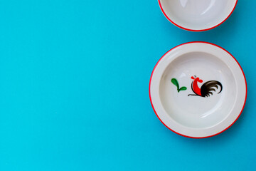 A collection of crockery sets made of porcelain in the blue background. The crockery has the image of a rooster.