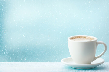 Fototapeta premium Warm cup of coffee on a snowy morning by the window in a cozy setting