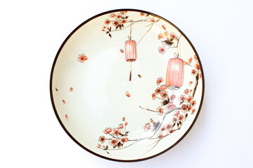 A photo of a white plate. It is made of porcelain and has oriental illustrations and motifs.