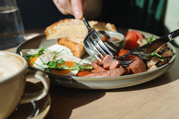 Close-up of a man enjoying an English breakfast in a cafe on a sunny morning.