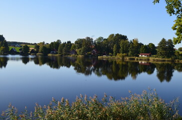 river landscape with reflection of trees on the water blue clear sky