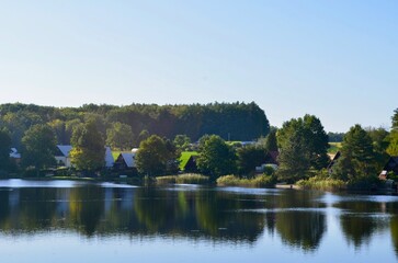 river landscape with reflection of trees on the water blue clear sky