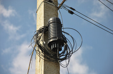 Coupling for connecting optical communication cables on a pole against the background of blue sky....