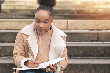 Young Woman Creatively Journaling on Stone Steps in  Quiet Urban Setting During Daylight