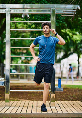 Man, portrait and stretching in park for fitness, warm up and ready for exercise with music. Athlete, equipment and workout at outdoor gym for fresh air, healthy body and start of training in Italy