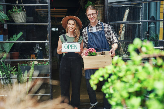 Man, woman and portrait at flower shop with open sign at startup, partnership and happy at front door. Couple, small business owner and nursery for plants, flowers and sustainable growth in England