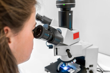 scientist looking through a microscope in a laboratory doing research, microbiological analysis, medicine. Scientist looking in microscope in laboratory