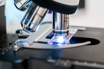 A microscope with a light on it, Man medical Doctor or research scientist looking through a microscope in a laboratory.science experiments, laboratory glassware containing chemical liquid for research