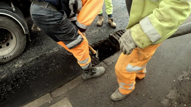 Urban Street Maintenance: Workers Cleaning Road Drainage using vacuum excavator in a Bustling City Area During the Day