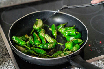 Tapas Klassiker Gebratene Pimientos de Padron werden in einer schwarzen Pfanne gebraten