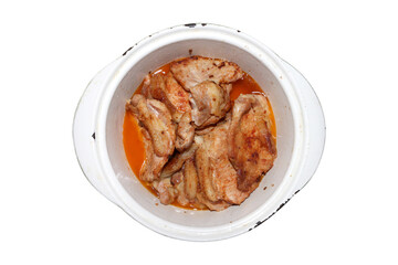 Stewed pork with a toasted crust.Stewed pork in a cast-iron dish on a white background.