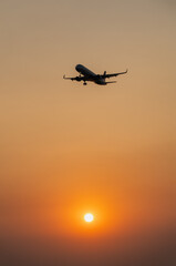 Passenger plane is landing on the background of the setting sun
