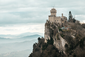 Guaita Tower in San Marino on a Cliff with Dramatic Clouds and Scenic Mountain Views
