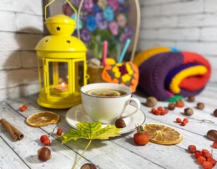 Cozy autumn photo with a cup of tea, flashlight, knitting, leaves and decor 