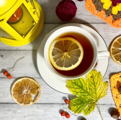 Cozy autumn photo with a cup of tea, flashlight, knitting, leaves and decor 