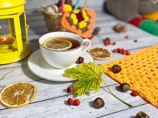 Cozy autumn photo with a cup of tea, flashlight, knitting, leaves and decor 