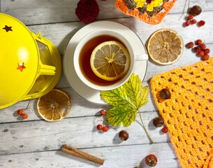 Cozy autumn photo with a cup of tea, flashlight, knitting, leaves and decor 