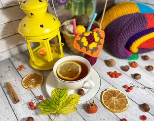 Cozy autumn photo with a cup of tea, flashlight, knitting, leaves and decor 