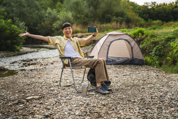 japanese woman sit in front of tent and have a video call on cellphone