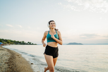 Young woman running or jogging on the beach at sunset