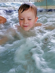 Pretty boy swimming in outdoor pool and have a fun with inflatable circle