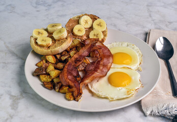 two fried eggs with home fries and bacon