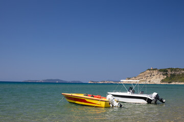 Two Motorboats Anchored in Clear Sea with Cliff View