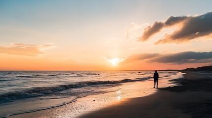 A man walks on the beach at sunset