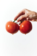 Two hands holding ripe tomatoes on a white background