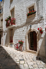 Charming stone building with red flowers and bicycle in Monopoli