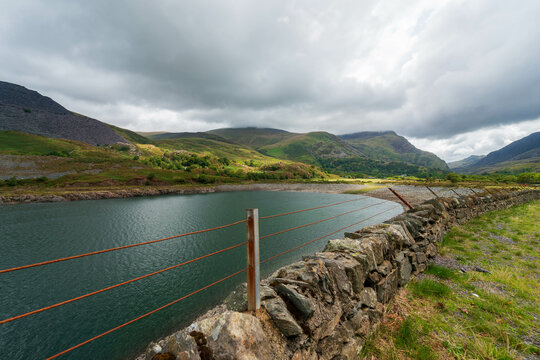 Dramatic view of Llyn Celyn reservoir and the Snowdonia mountains under a stormy sky in Wales.