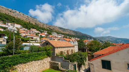 Obraz premium Charming Croatian village nestled on hillside with traditional terracotta roofs & lush greenery.