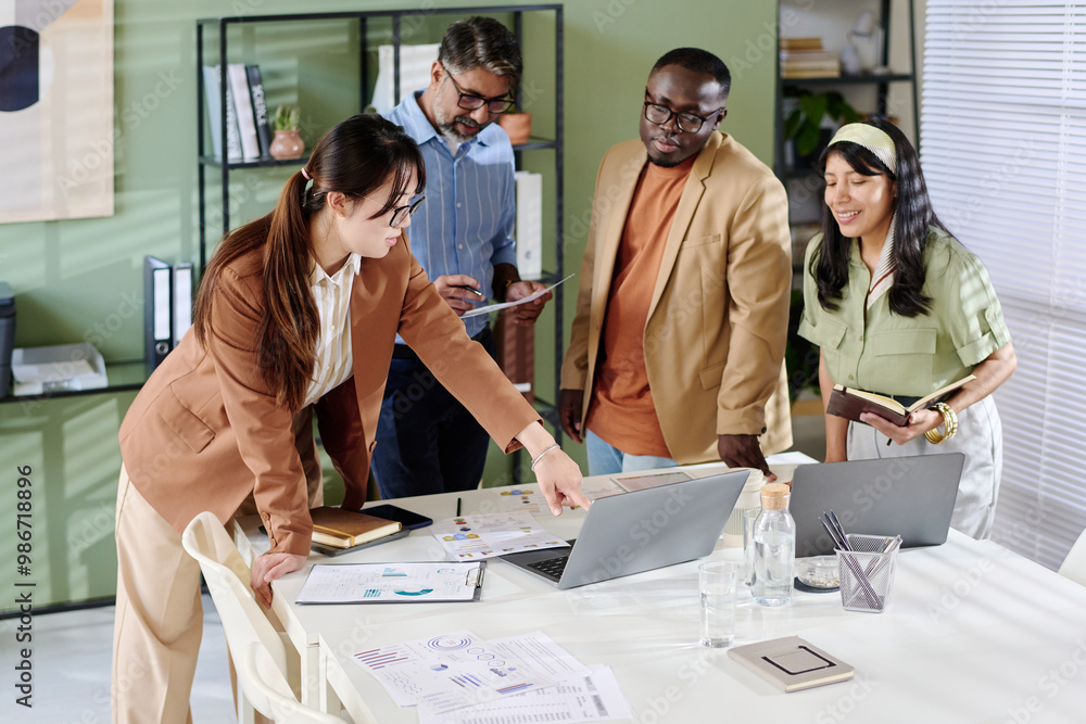 Poster group of diverse colleagues engaging in collaborative discussion around office table, surrounded by 