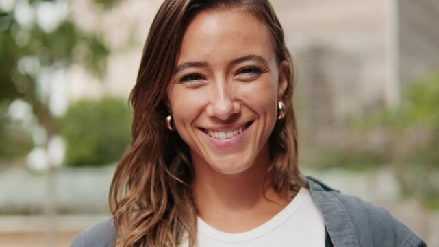 Close-up of European young woman, pretty female studet smiling outdoors with blured urban background