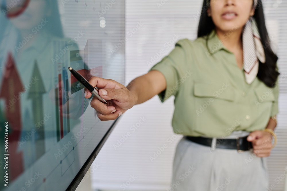 Poster Woman pointing at data on interactive display during presentation in office environment showing professional attire and engagement with the technology while explaining analytics information