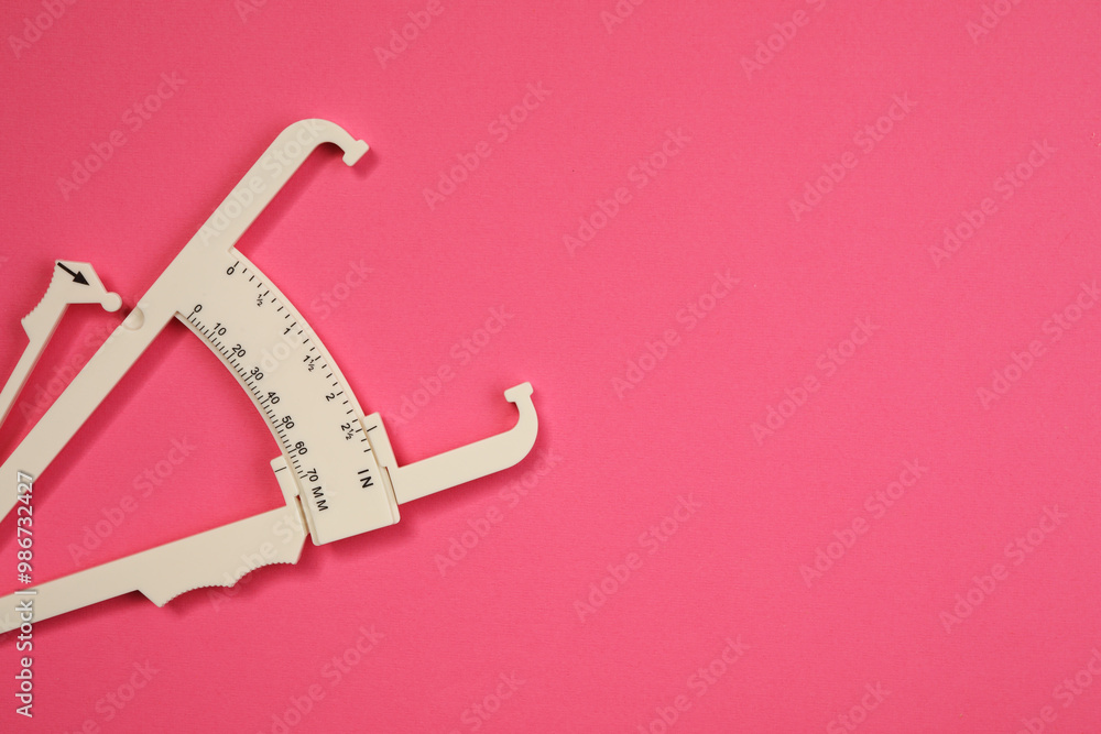 Poster Plastic body fat caliper on pink background, top view. Space for text