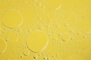 Sample of cosmetic oil on yellow background, macro view