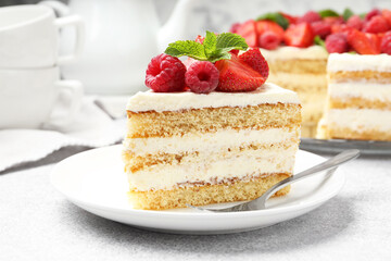 Tasty sponge cake with fresh berries and mint served on light gray table, closeup