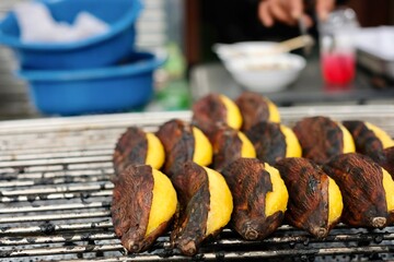 Grilled kluay khai (ladyfinger bananas) still in their skins for sale at the morning wet market at Soi 20 in Silom - Bang Rak, Bangkok, Thailand