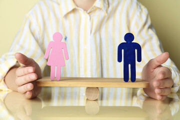 Gender equality concept. Woman with male and female figures on scales against light yellow...