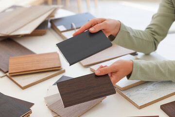 Woman choosing wooden flooring among different samples at table, closeup