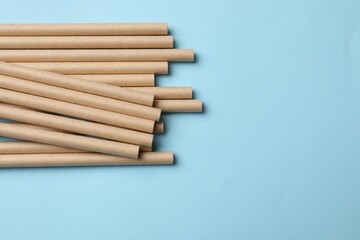 Bamboo drinking straws on light blue background, top view. Space for text