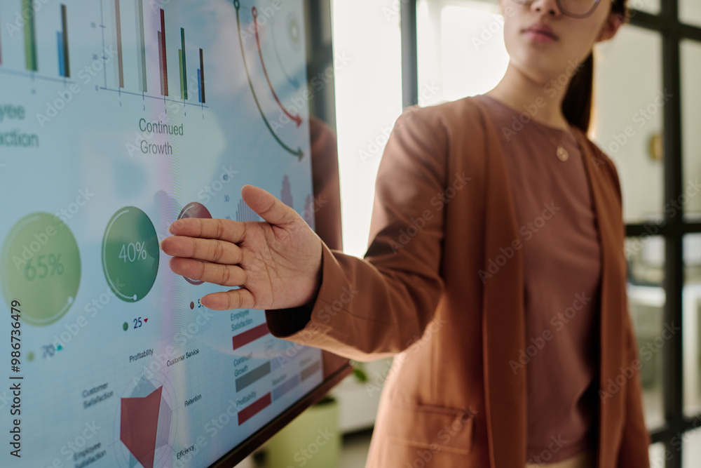 Poster Person presenting data on an interactive screen displaying various growth metrics and charts in modern office environment