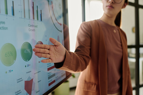 Person presenting data on an interactive screen displaying various growth metrics and charts in modern office environment