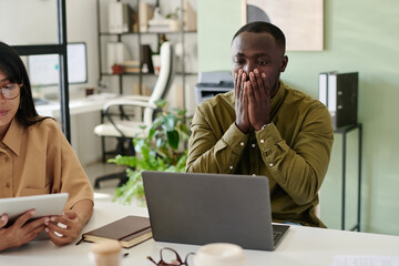 Colleagues working on project while using laptop and digital tablet in modern office setting with indoor plants and contemporary furnishings, highlighting business collaboration and teamwork