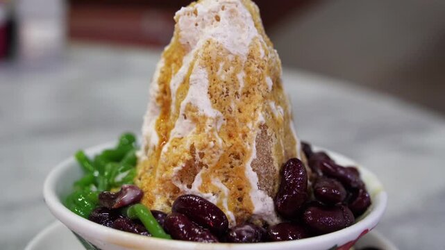 Close-up view of the cendol dessert with gula Melaka syrup. Cendol is made from crushed ice cubes, jelly, coconut milk, and red beans.